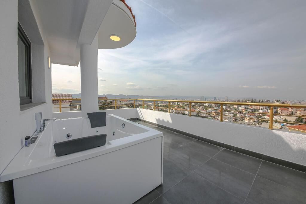 Een moderne badkamer met een badkuip, wastafel en een raam met uitzicht op een stadsgezicht.