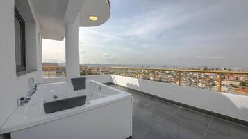 Een moderne badkamer met een badkuip, wastafel en een raam met uitzicht op een stadsgezicht.