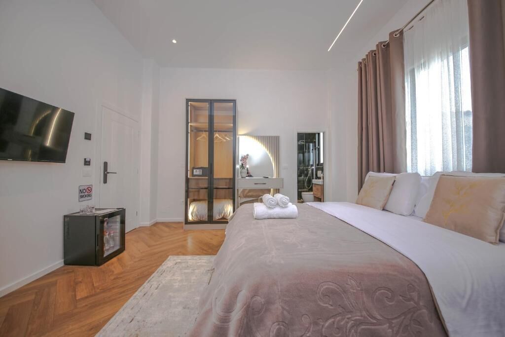 A bedroom with a bed, a TV, a wardrobe, and a mirror.