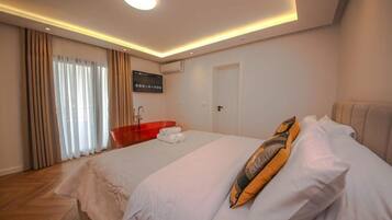 A hotel room with a bed, a red bathtub, a flat-screen TV, and a ceiling light.