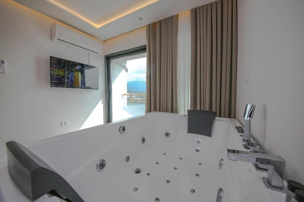 A modern bathroom with a large bathtub, a shower area, and a window with curtains.