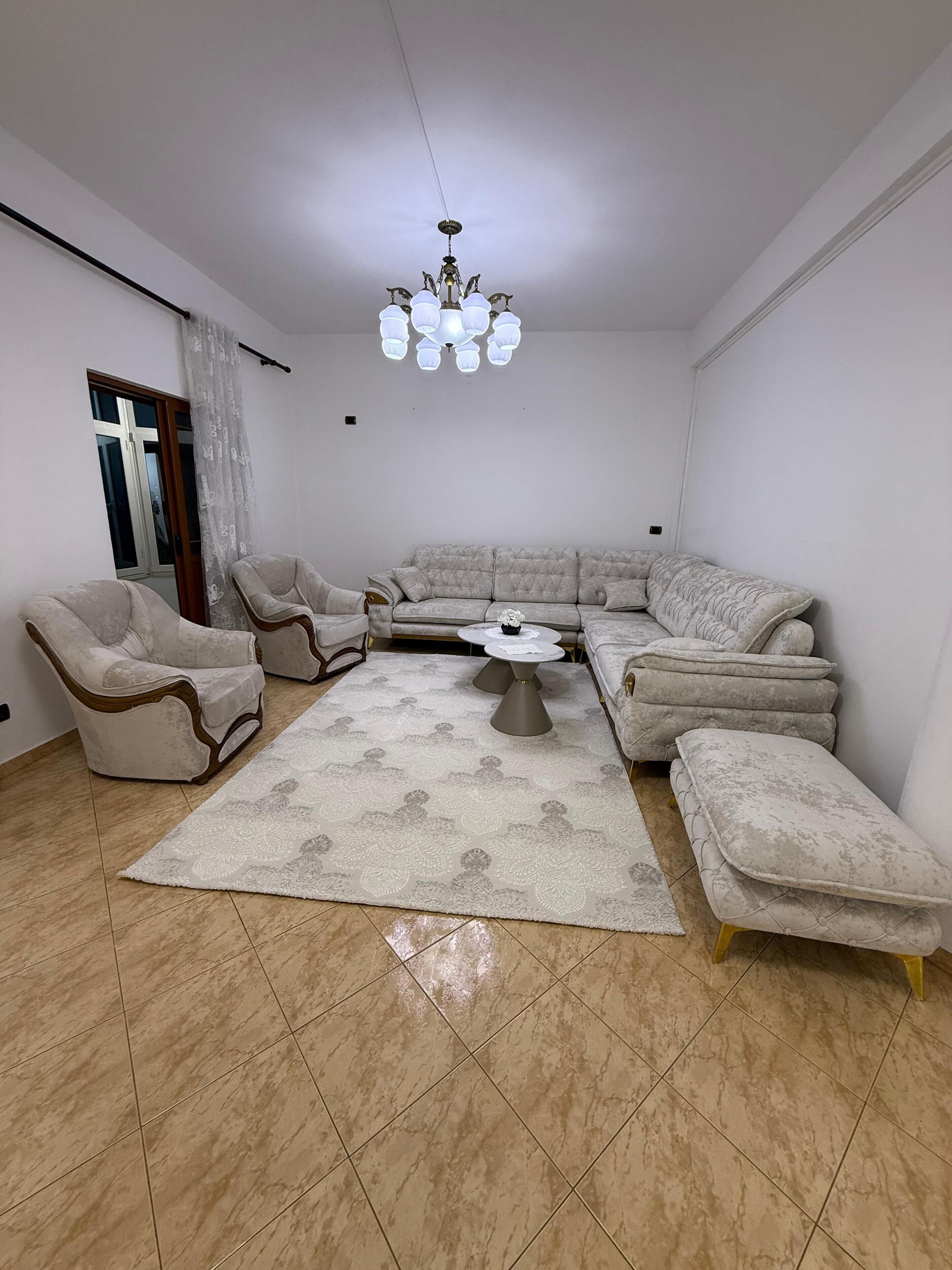 A living room with a sectional sofa, two armchairs, a coffee table, and a chandelier.