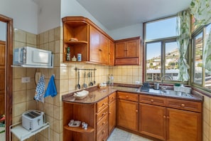 A kitchen with wooden cabinets, a microwave, a toaster, and a window with a view of buildings.