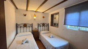 Une chambre avec deux lits simples, une table de chevet, un miroir et une fenêtre donnant sur un paysage agréable.