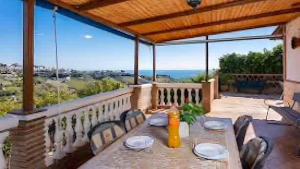 Un espace de restauration en plein air avec une table dressée pour deux personnes, une plante en pot et une vue sur le paysage.