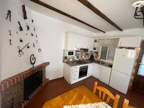 A compact kitchen with white cabinets, a tiled backsplash, a microwave, a stove, and a refrigerator.