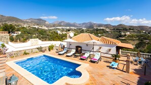 Une piscine avec des chaises longues, un espace patio et une vue sur les montagnes.