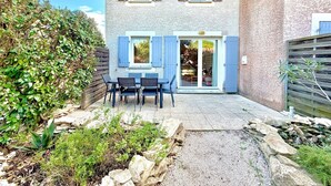 A two-story building with a patio area featuring a table and chairs. - Terrasse du Sud, 4 guests, Pool in Calvisson (Calvisson)