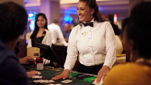 A casino dealer at a blackjack table with players. - The Crescent (Verona)