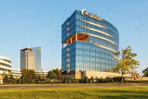 A modern hotel with a curved facade, multiple balconies, and a prominent logo. - The Crescent (Verona)