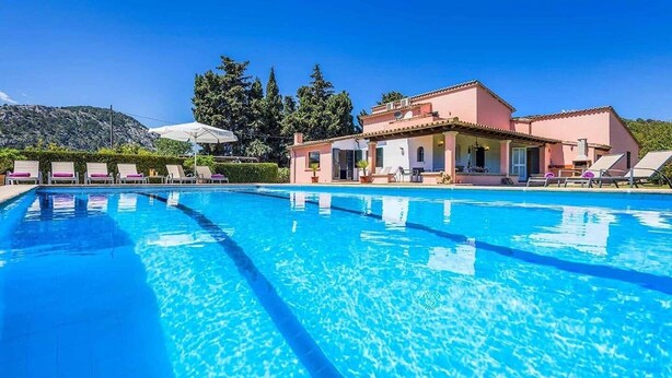 A swimming pool with lounge chairs and a building in the background. - Villa Patricia (Pollença)