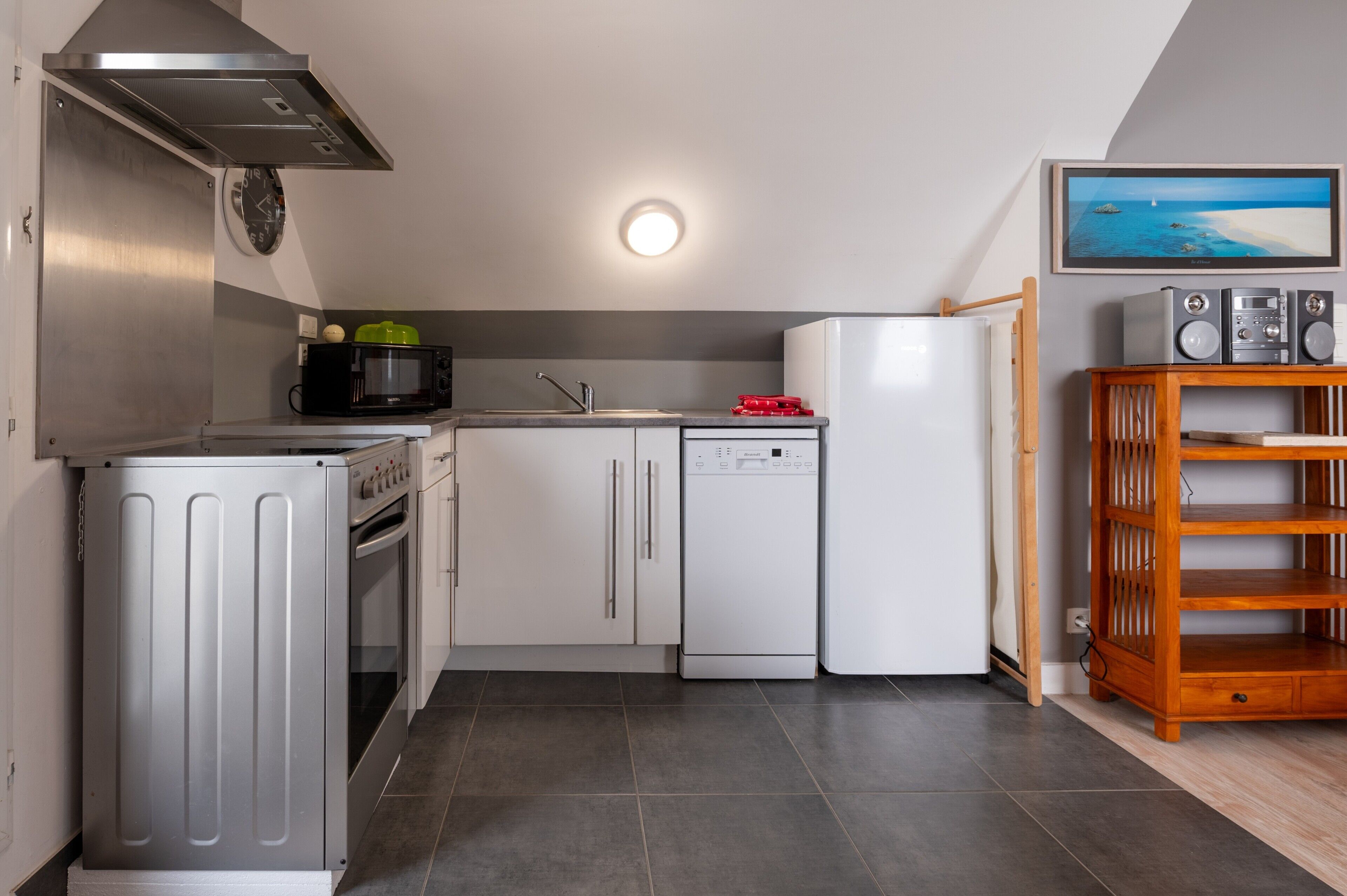 A modern kitchen with stainless steel appliances, a microwave, a dishwasher, and a wooden TV stand.