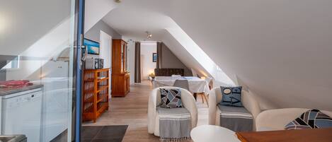 Ein Dachzimmer mit einer Küche, einem Essbereich und Sitzgelegenheiten.