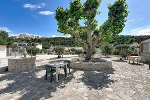 A courtyard with stone flooring, a central tree, and outdoor seating.