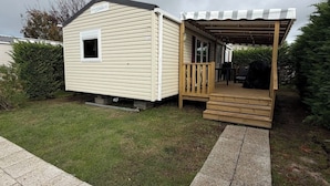 En campingvogn med overdækket veranda og lille terrasse.