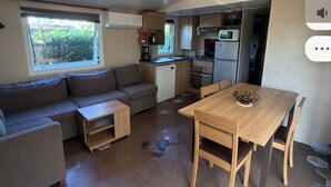 En kompakt bolig med et tekøkken, spiseplads og opholdsområde med sofa og bord.