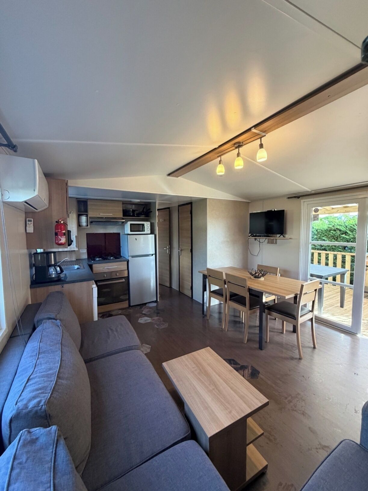 Um espaço compacto para viver, com cozinha compacta, área de refeições e espaço de estar com sofá e mesa de centro.