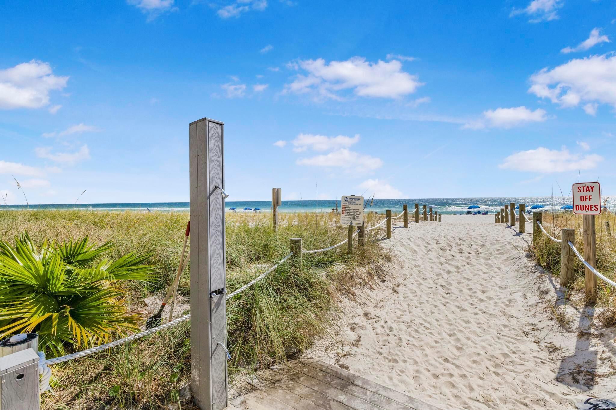 A sandy beach path leading to the ocean with a 'Stay Off Dunes' sign.