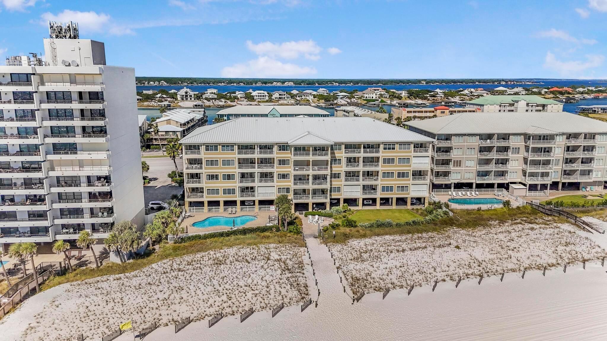A beachfront hotel with multiple balconies, a swimming pool, and a view of the ocean.