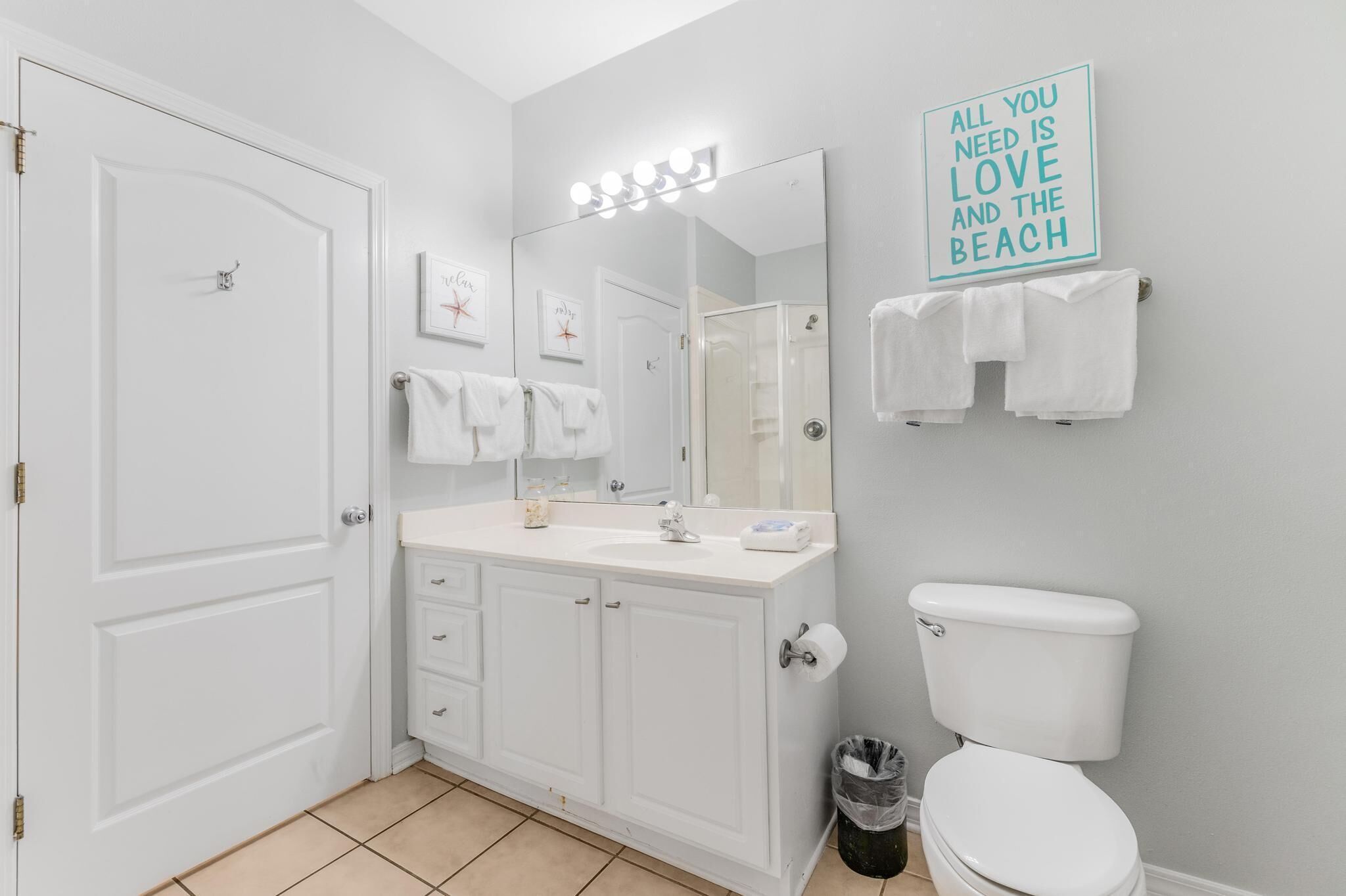 A bathroom with a white vanity, a mirror, a toilet, and a towel rack.