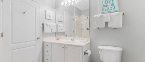 A bathroom with a white vanity, a mirror, a toilet, and a towel rack.