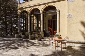 A building with arched windows, stone steps, and outdoor seating.