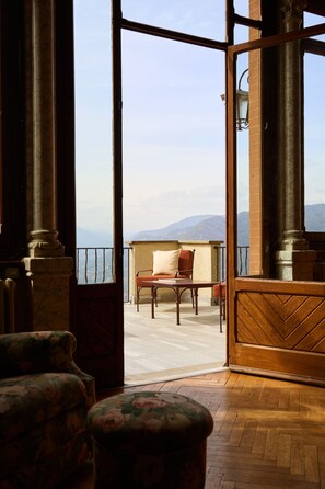 A room with a view of mountains, a wooden floor, a chair, and a table.
