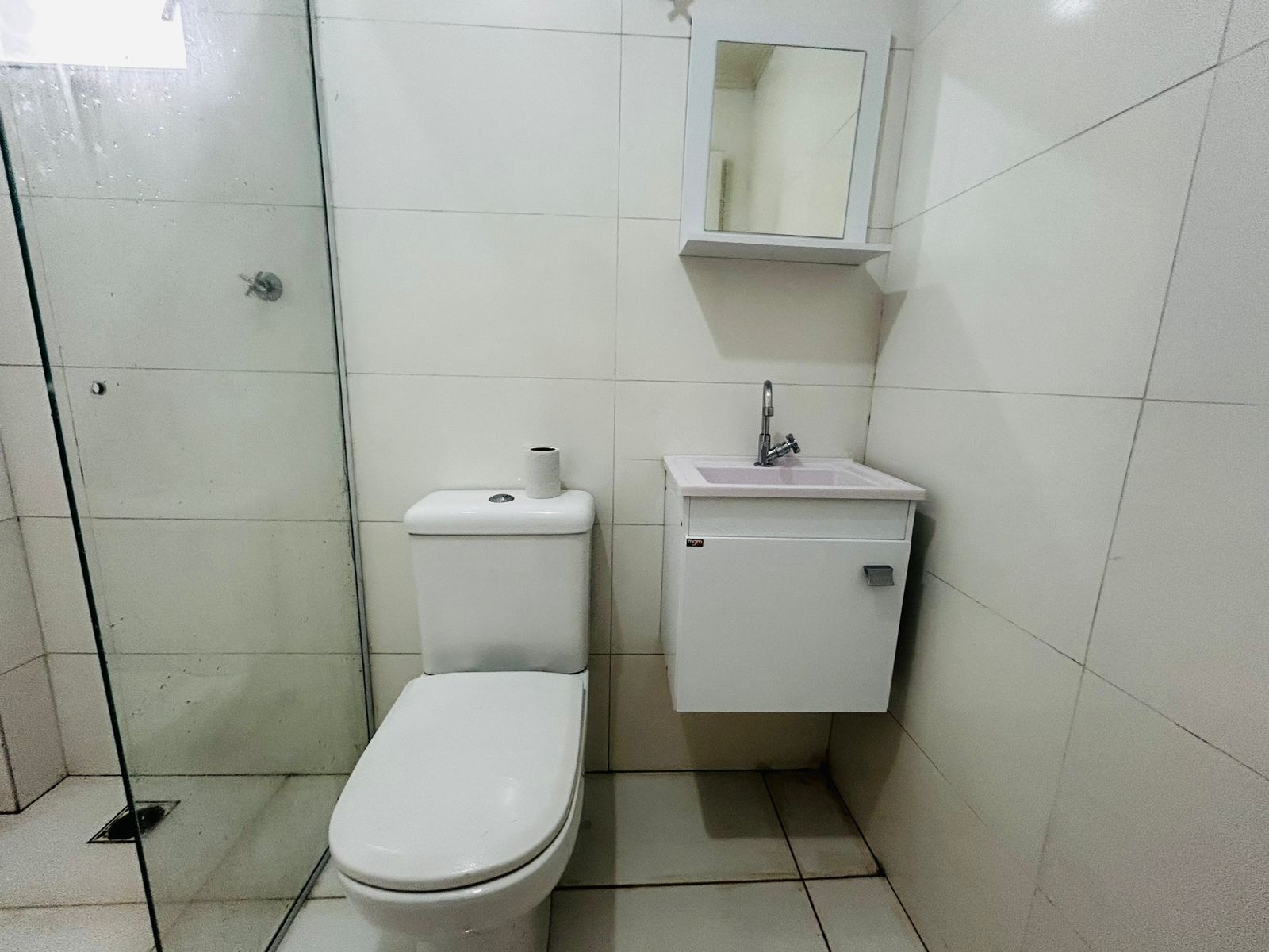 Un baño pequeño y limpio con inodoro, lavamanos y espejo.