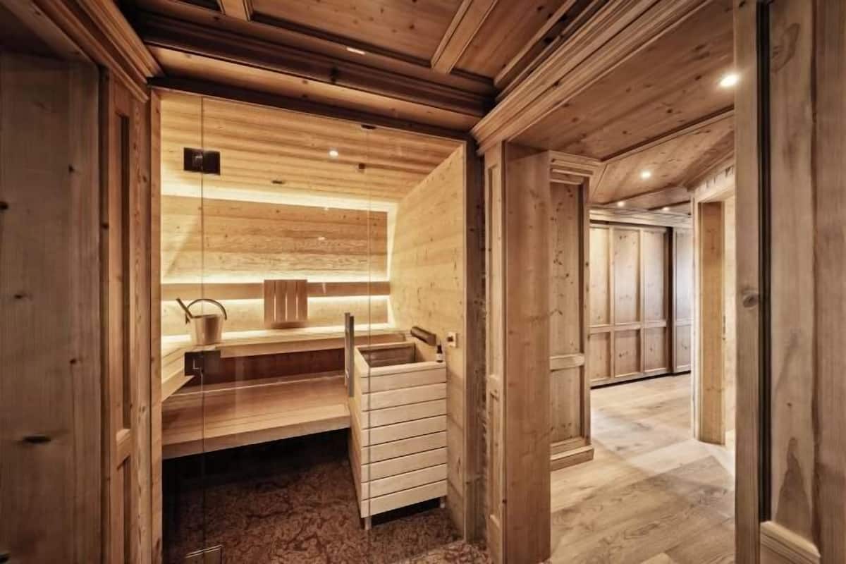 Eine Holzsauna mit einer Bank, einem Waschbecken und einem kleinen Fenster.