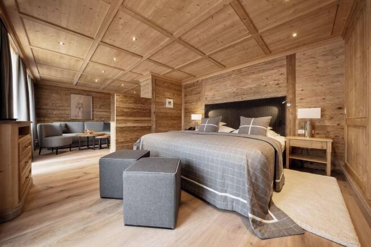 Ein Schlafzimmer mit Holzwandverkleidung, einem großen Bett, Nachttischen, einem Sofa und einem kleinen Tisch.
