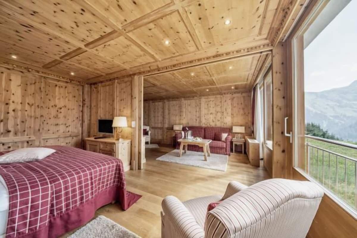 Eine Holzhütte mit einem Bett, einer Couch, einem Tisch und einem Fernseher.
