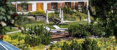 A hotel with a garden, outdoor seating, and a pool area.