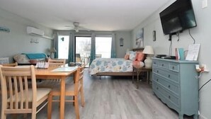 A room with a bed, a TV mounted on the wall, a desk with a chair, and a dresser. - Condo 224 Beautiful Cedar key (Cedar Key)