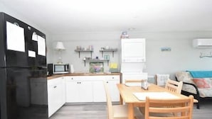A compact kitchen with white cabinets, a black refrigerator, a microwave, and a dining area with a wooden table and chairs. - Condo 224 Beautiful Cedar key (Cedar Key)