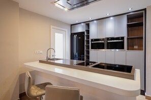 Una cucina moderna con forno integrato, frigorifero in acciaio inossidabile e un piano di lavoro elegante.