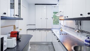 A modern kitchen with white cabinets, a black countertop, and a stainless steel sink.
