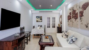 A living room with a flat-screen TV, wooden entertainment unit, sofa, and artwork on the walls.