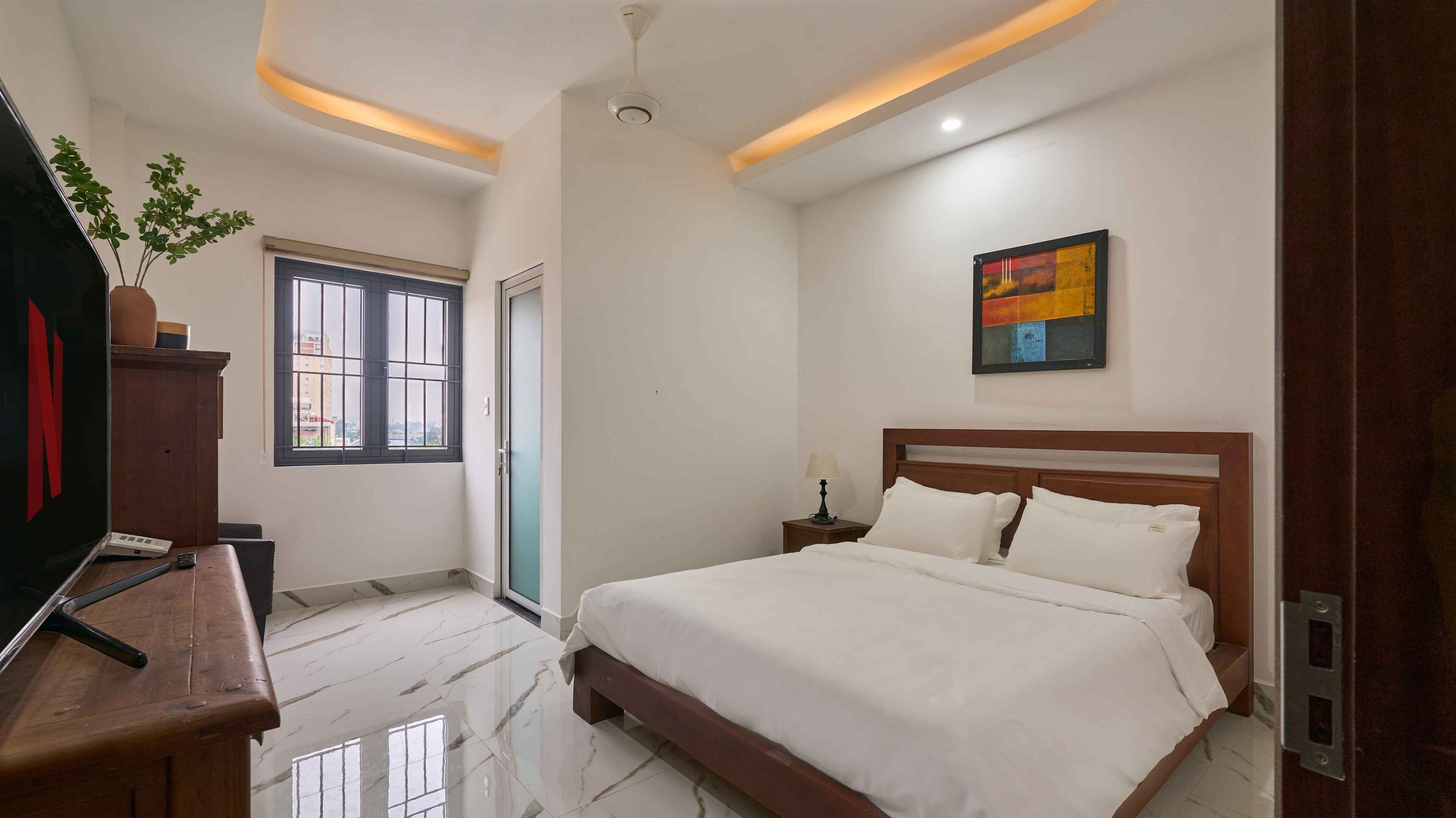 Une chambre d’hôtel avec un lit, une table de chevet, une lampe et un tableau au mur.