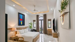 A modern hotel room with a large bed, a desk, a chair, a TV, and a balcony with curtains. - Green Riverside Hotel (Ho Chi Minh City)
