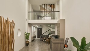 A spacious, modern interior with a central staircase, a dining area, and a reception desk. - Green Riverside Hotel (Ho Chi Minh City)