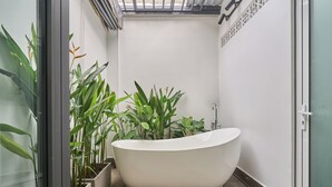 A modern bathroom with a freestanding bathtub, potted plants, and a glass shower enclosure. - Green Riverside Hotel (Ho Chi Minh City)