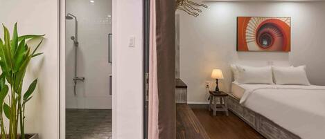 A hotel room with a bed, bedside table, lamp, and a painting on the wall.