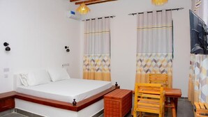 Un dormitorio con cama, muebles de madera y cortinas estampadas.