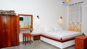 A bedroom with a bed, a wooden wardrobe, a desk, and a small stool. - Charming 1-bedroom apartment in enchanting Jambiani with AC (Jambiani)