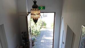 A hallway with a checkered floor, a staircase, a hanging light fixture, and a door leading outside. - Bright 2-room studio with a view, private bathroom, kitchen, and a spacious, sunny balcony (Bergen aan Zee)