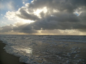 A beach with waves and a cloudy sky.