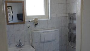 A small, compact bathroom with a white sink, toilet, and a window above the sink. - Bright 2-room studio with a view, private bathroom, kitchen, and a spacious, sunny balcony (Bergen aan Zee)