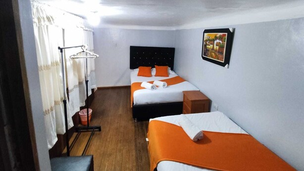 A small, clean room with two beds, a wooden floor, a wall-mounted picture, and a window with curtains. - SAPHY APARTAMENTS INN MINUTES AWAY FROM THE PLAZA DE ARMAS (Cusco)