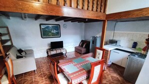 A dining area with a wooden table and chairs, a sofa, a small kitchen area with a microwave, and a clock on the wall. - SAPHY APARTAMENTS INN MINUTES AWAY FROM THE PLAZA DE ARMAS (Cusco)