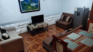 A room with a sofa, a chair, a bed, a TV on a stand, a clock on the wall, and a refrigerator. - SAPHY APARTAMENTS INN MINUTES AWAY FROM THE PLAZA DE ARMAS (Cusco)